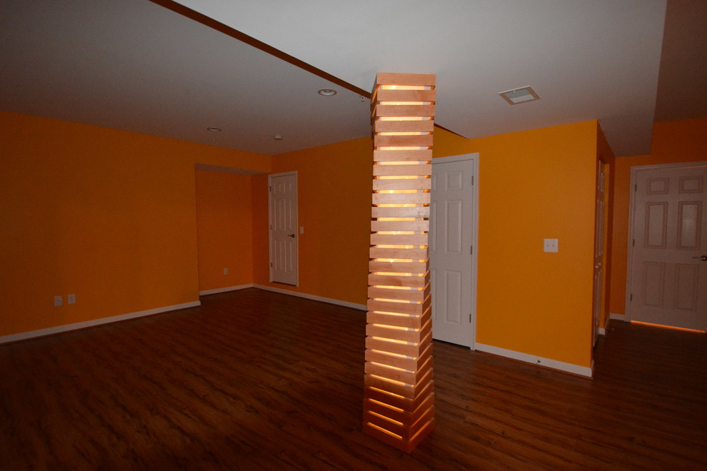 Inspiration for an expansive transitional fully buried basement in DC Metro with orange walls, dark hardwood floors and no fireplace.