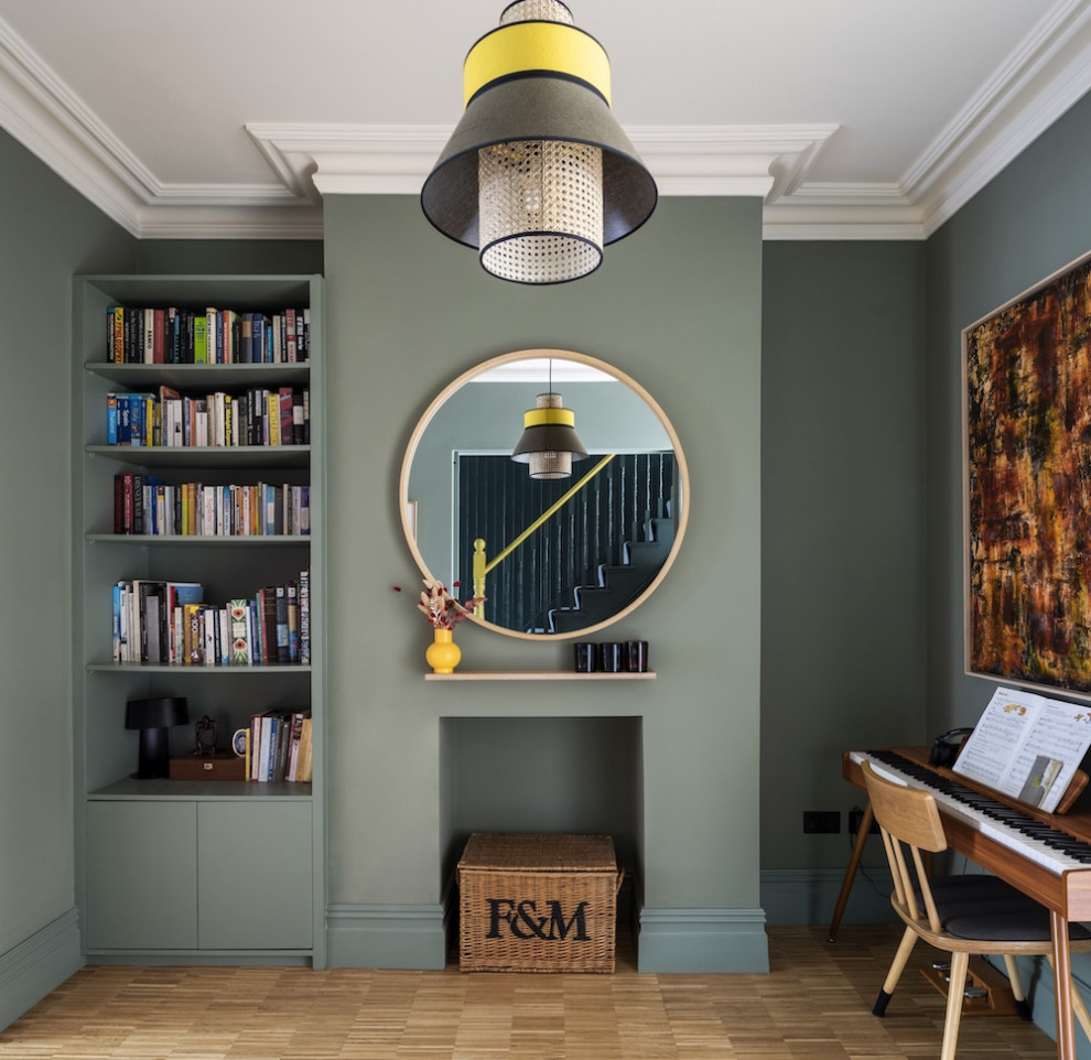Réalisation d'une salle à manger ouverte sur le salon design avec un mur vert et parquet clair.