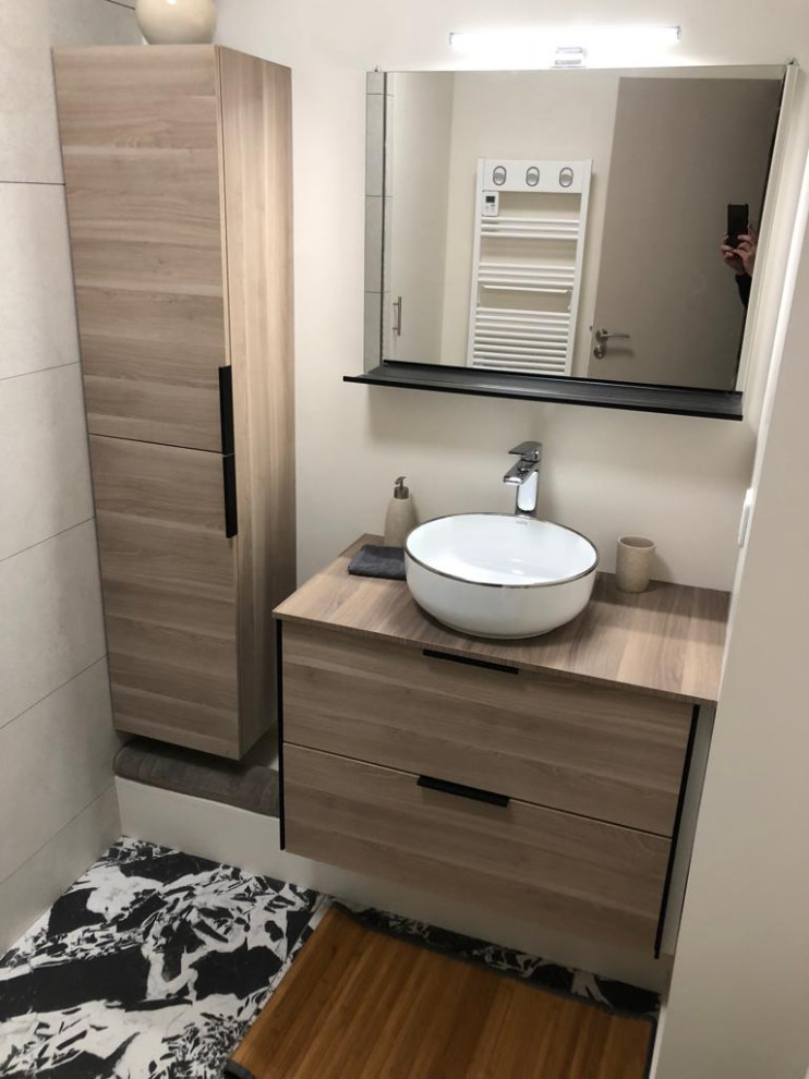 This is an example of a small modern ensuite bathroom in Other with beaded cabinets, beige cabinets, a built-in shower, a wall mounted toilet, beige tiles, stone tiles, beige walls, concrete flooring, a built-in sink, stainless steel worktops, multi-coloured floors, an open shower, white worktops, a laundry area, a single sink and a floating vanity unit.