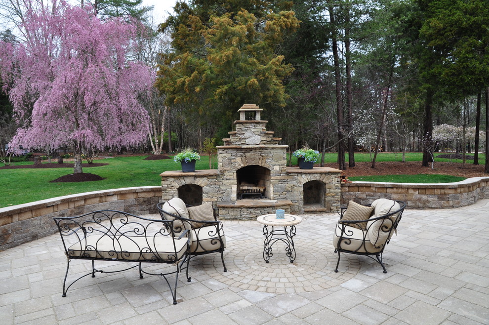 This is an example of a large traditional backyard patio in DC Metro with a fire feature, natural stone pavers and no cover.