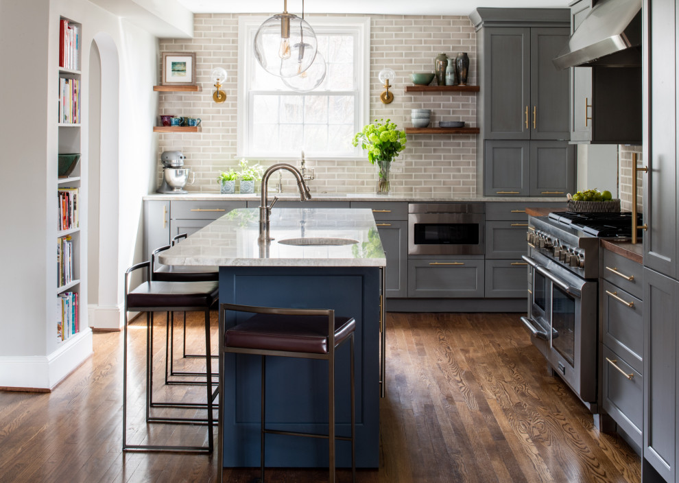 Transitional l-shaped kitchen in DC Metro with an undermount sink, shaker cabinets, grey cabinets, grey splashback, subway tile splashback, stainless steel appliances, dark hardwood floors, with island, brown floor and white benchtop.