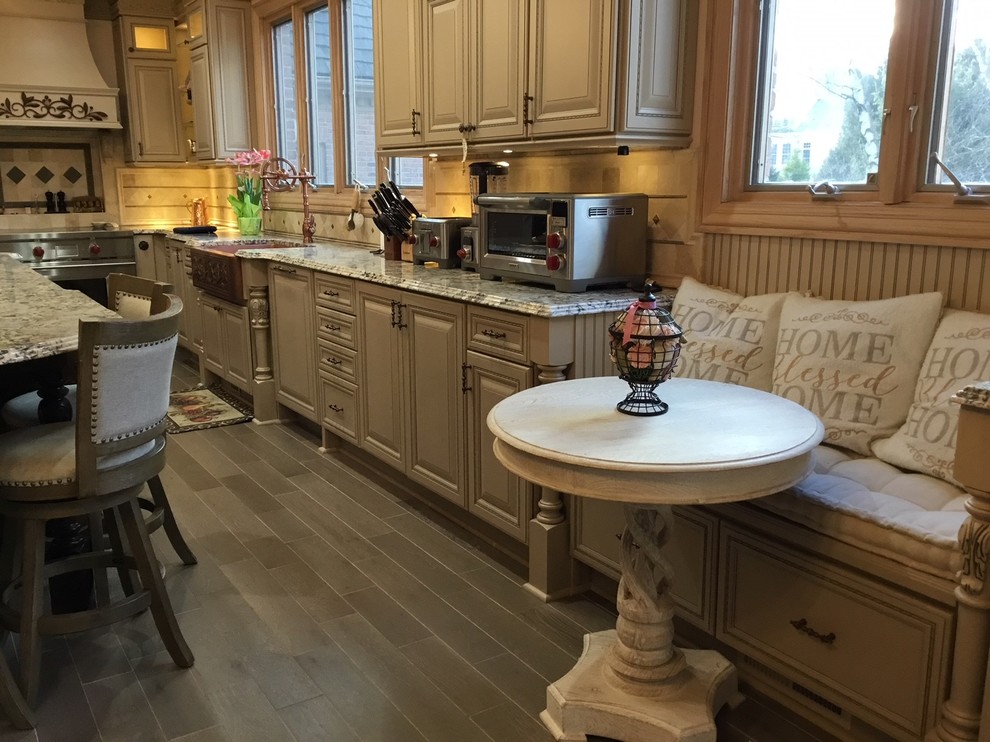 This is an example of a large l-shaped eat-in kitchen in Other with beige cabinets, stainless steel appliances, with island and grey floor.