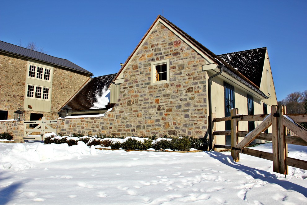 Photo of a mid-sized country two-storey beige exterior in Philadelphia with stone veneer and a gable roof.