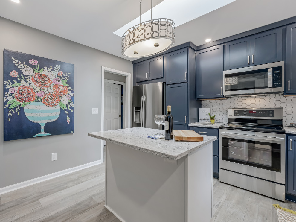 Example of a large transitional l-shaped kitchen design in Raleigh with an undermount sink, recessed-panel cabinets, quartz countertops, porcelain backsplash, stainless steel appliances and an island