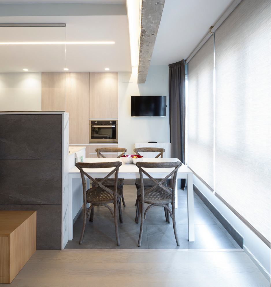 Photo of a mid-sized transitional open plan dining in Bilbao with white walls, ceramic floors and no fireplace.