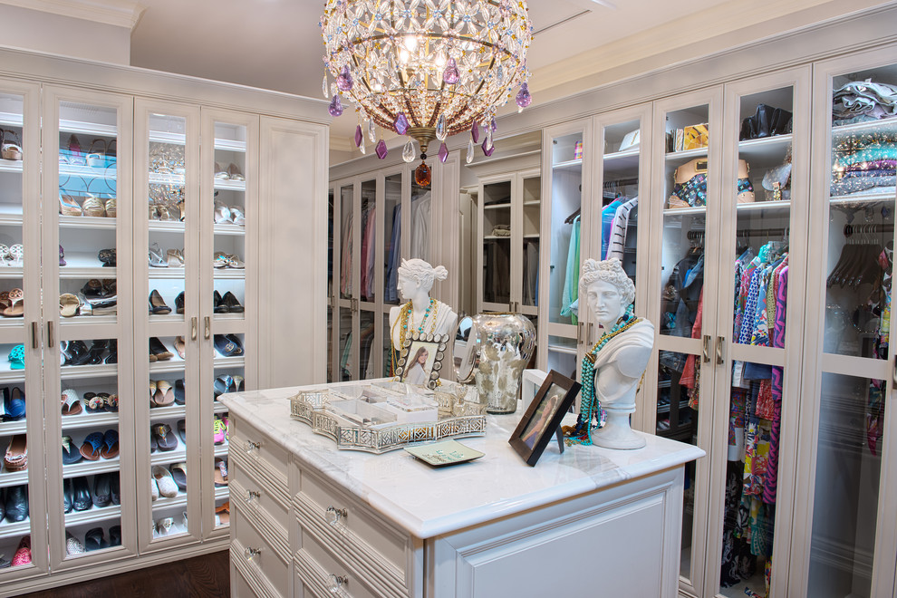 Photo of a mid-sized traditional women's dressing room in Other with glass-front cabinets, white cabinets and dark hardwood floors.