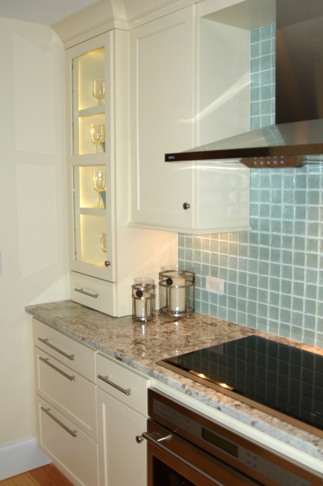 This is an example of a small beach style galley kitchen in Boston with an undermount sink, recessed-panel cabinets, white cabinets, granite benchtops, stainless steel appliances, light hardwood floors and no island.