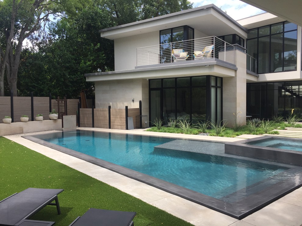 Photo of a large modern side yard custom-shaped infinity pool in Dallas with stamped concrete.