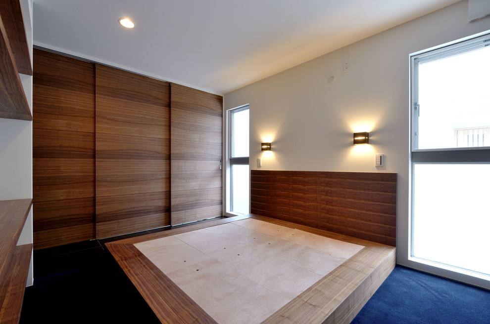 Medium sized modern master bedroom in Tokyo with white walls, carpet, no fireplace and blue floors.
