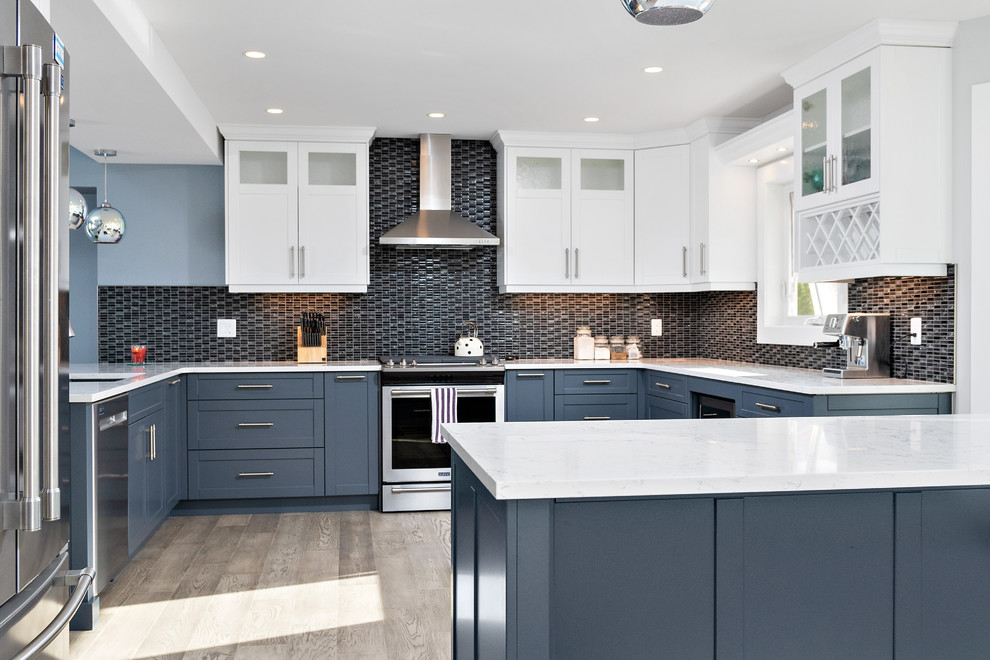 Eat-in kitchen - large transitional u-shaped medium tone wood floor and gray floor eat-in kitchen idea with an undermount sink, shaker cabinets, blue cabinets, quartz countertops, black backsplash, glass tile backsplash, stainless steel appliances, an island and white countertops