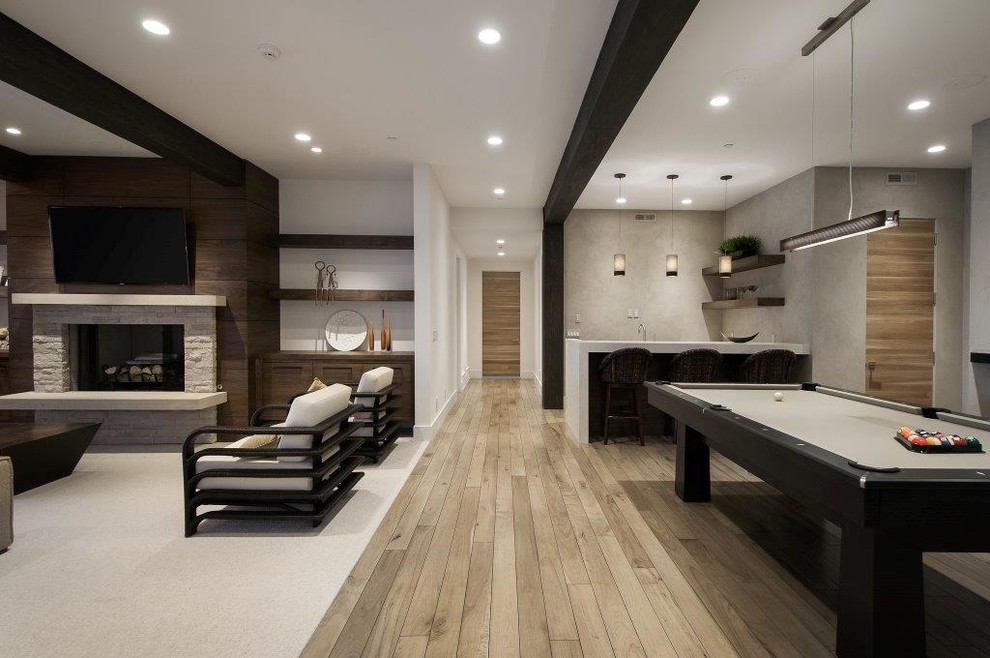 Design ideas for a large contemporary open concept family room in Salt Lake City with a game room, white walls, medium hardwood floors, a standard fireplace, a stone fireplace surround and a wall-mounted tv.