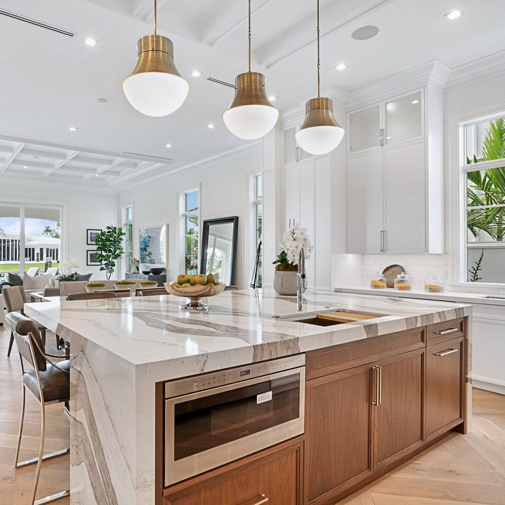 Photo of a traditional open plan kitchen in Miami with flat-panel cabinets, quartz benchtops, stainless steel appliances, with island and white benchtop.