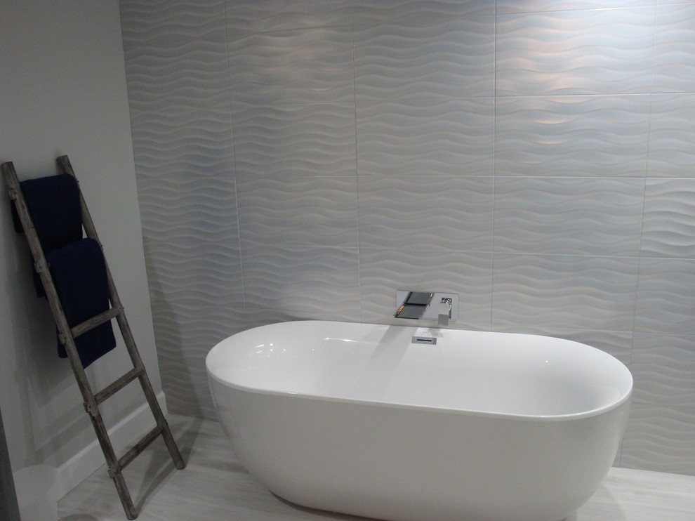 This is an example of a mid-sized contemporary master bathroom in Miami with a freestanding tub, blue tile, porcelain tile, grey walls, porcelain floors and grey floor.