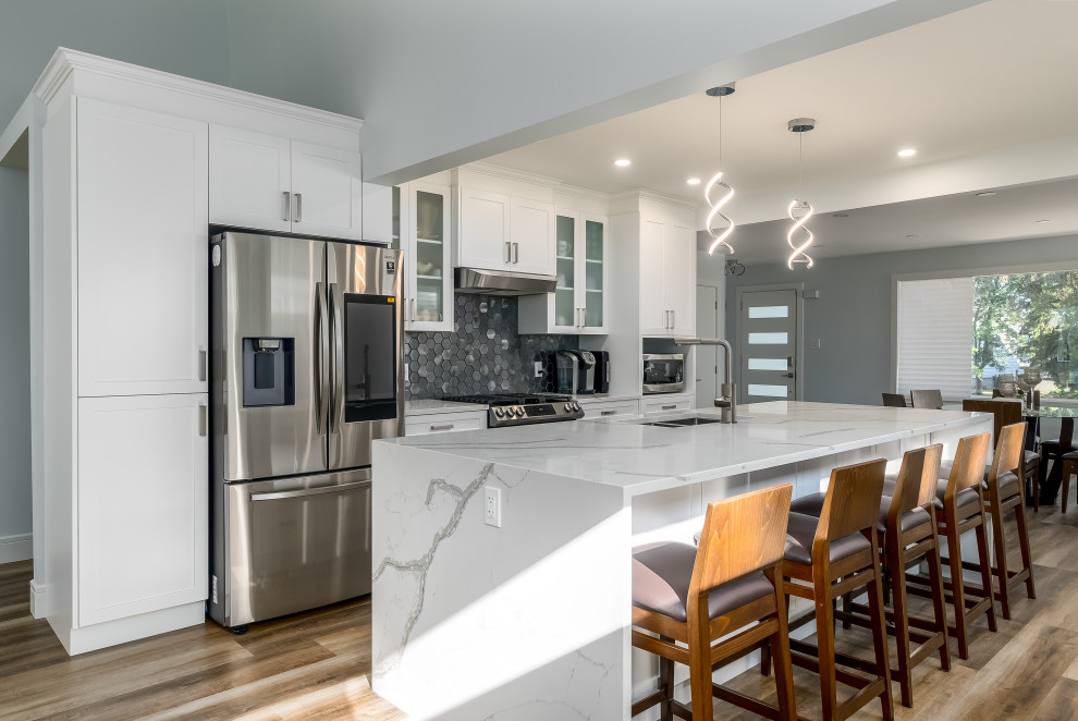 Transitional kitchen photo in Edmonton with shaker cabinets, white cabinets, quartzite countertops, gray backsplash, cement tile backsplash, stainless steel appliances, an island and white countertops