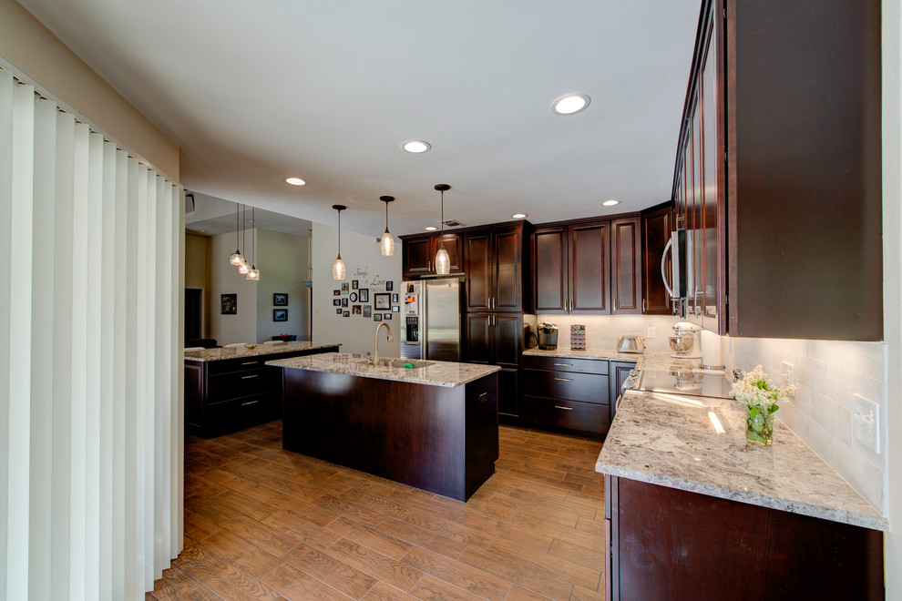 Eat-in kitchen - traditional ceramic tile eat-in kitchen idea in Dallas with raised-panel cabinets, dark wood cabinets, granite countertops, beige backsplash, stone tile backsplash, stainless steel appliances and two islands