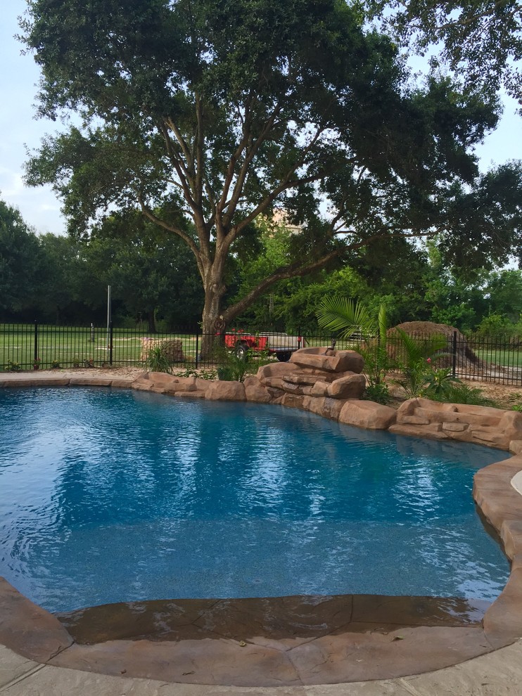 Inspiration for a mid-sized transitional backyard stamped concrete and custom-shaped lap pool fountain remodel in Houston