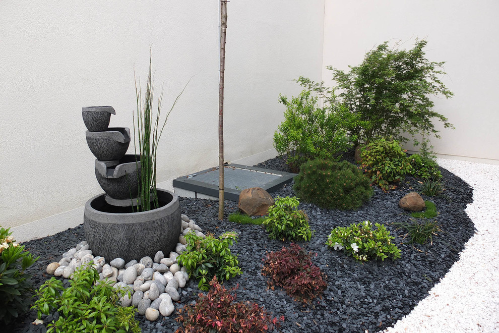 Inspiration for a mid-sized asian backyard partial sun garden in Paris with a water feature and gravel.
