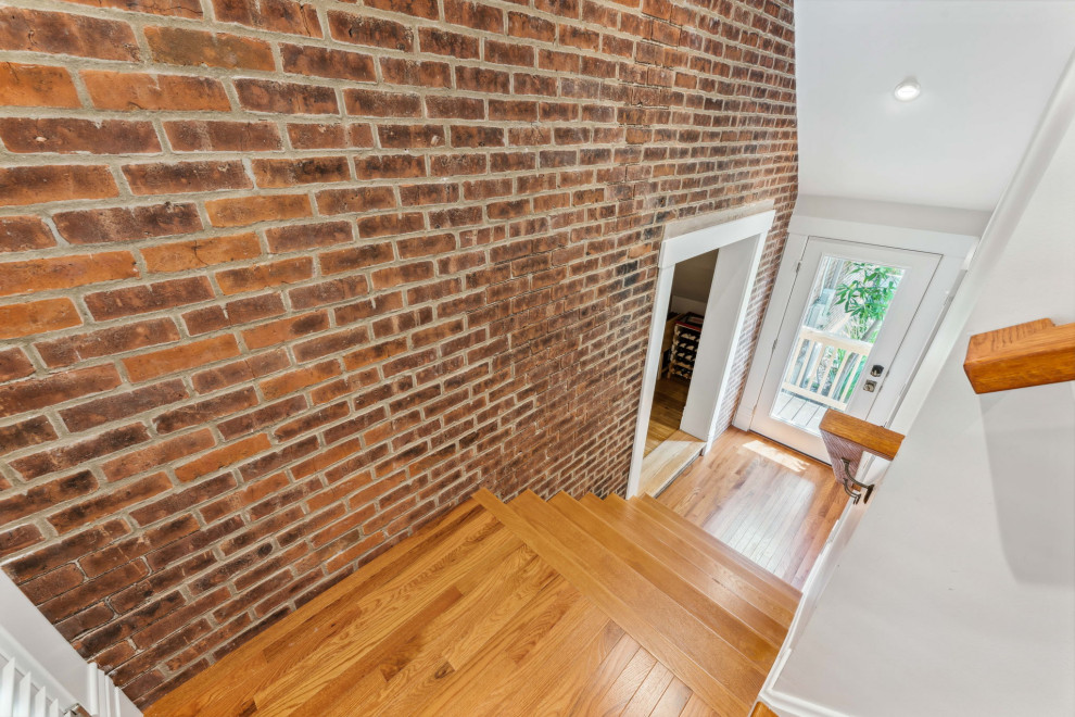 Mid-sized traditional wood l-shaped staircase in Columbus with painted wood risers, wood railing and brick walls.
