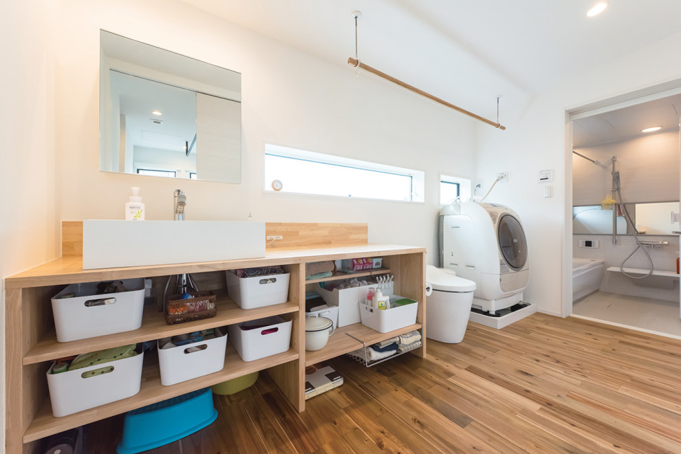 This is an example of a mid-sized industrial single-wall utility room in Tokyo Suburbs with a drop-in sink, open cabinets, brown cabinets, solid surface benchtops, white walls, medium hardwood floors, an integrated washer and dryer, brown floor and brown benchtop.