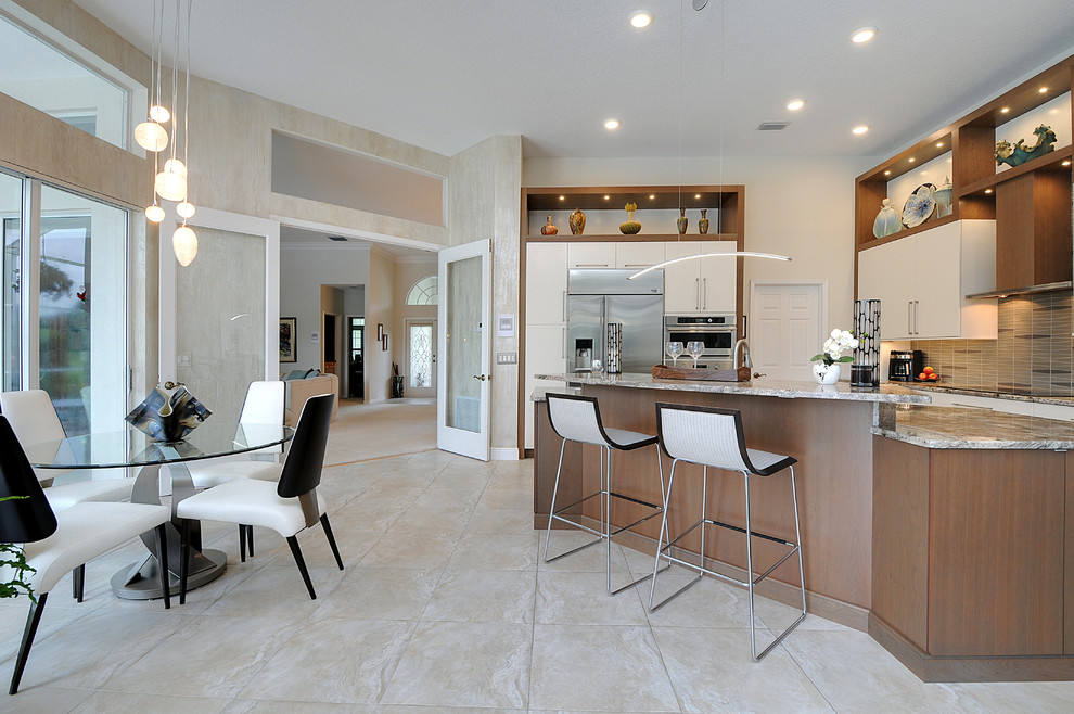 Design ideas for a large contemporary l-shaped open plan kitchen in Tampa with an undermount sink, flat-panel cabinets, granite benchtops, grey splashback, glass tile splashback, stainless steel appliances, porcelain floors and with island.
