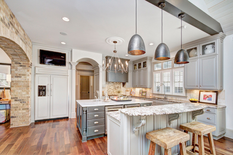 Design ideas for a traditional u-shaped kitchen in Charlotte with an undermount sink, raised-panel cabinets, grey cabinets, stainless steel appliances, medium hardwood floors, with island, brown floor and grey benchtop.