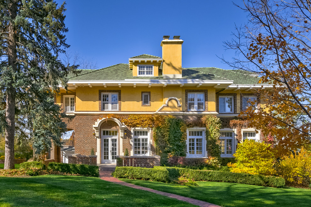 Photo of a large traditional two-storey brick yellow exterior in Omaha with a hip roof.