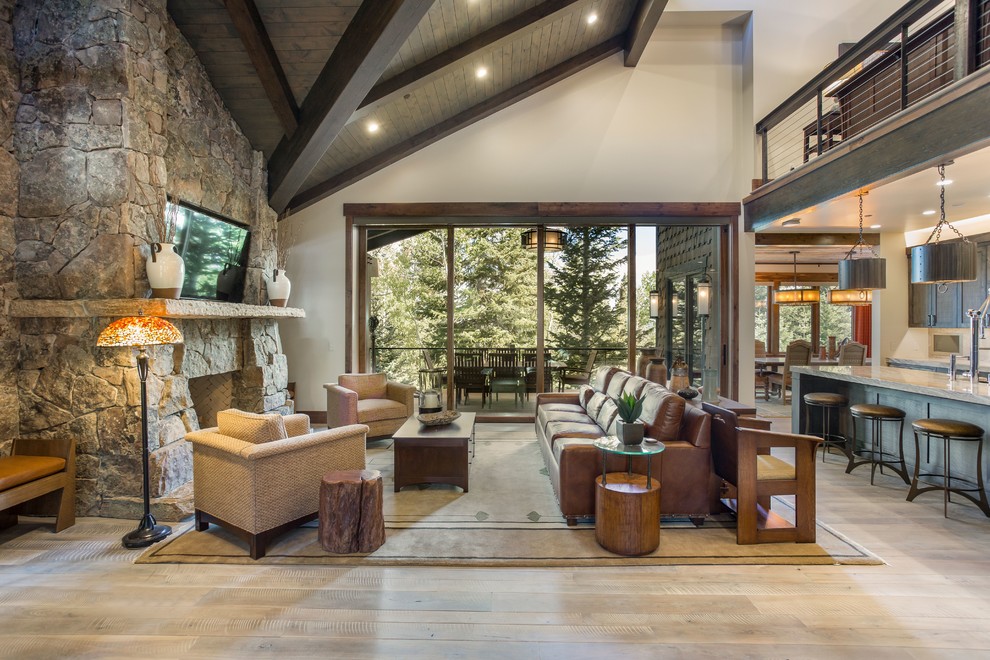 Photo of a country open concept living room in Salt Lake City with grey walls, medium hardwood floors, a standard fireplace, a stone fireplace surround and brown floor.