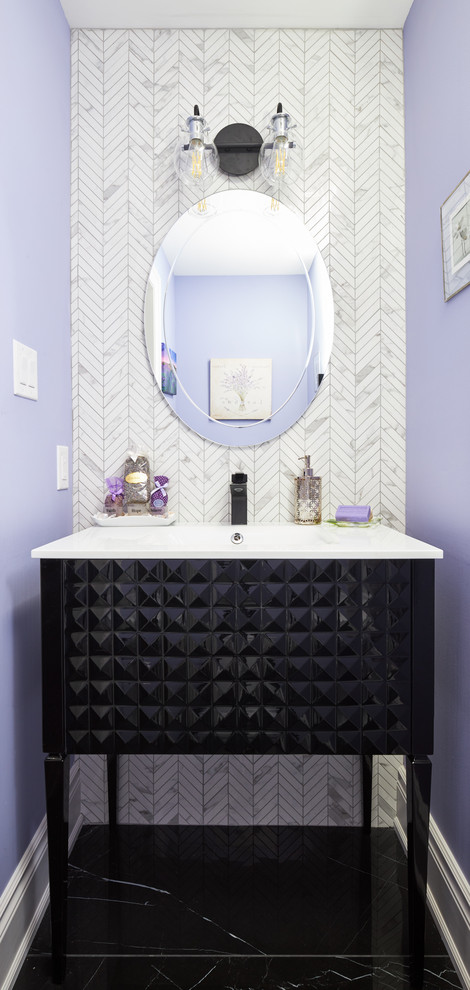 This is an example of a small transitional powder room in Toronto with furniture-like cabinets, black cabinets, a one-piece toilet, white tile, marble, purple walls, porcelain floors, an integrated sink, engineered quartz benchtops, black floor and white benchtops.
