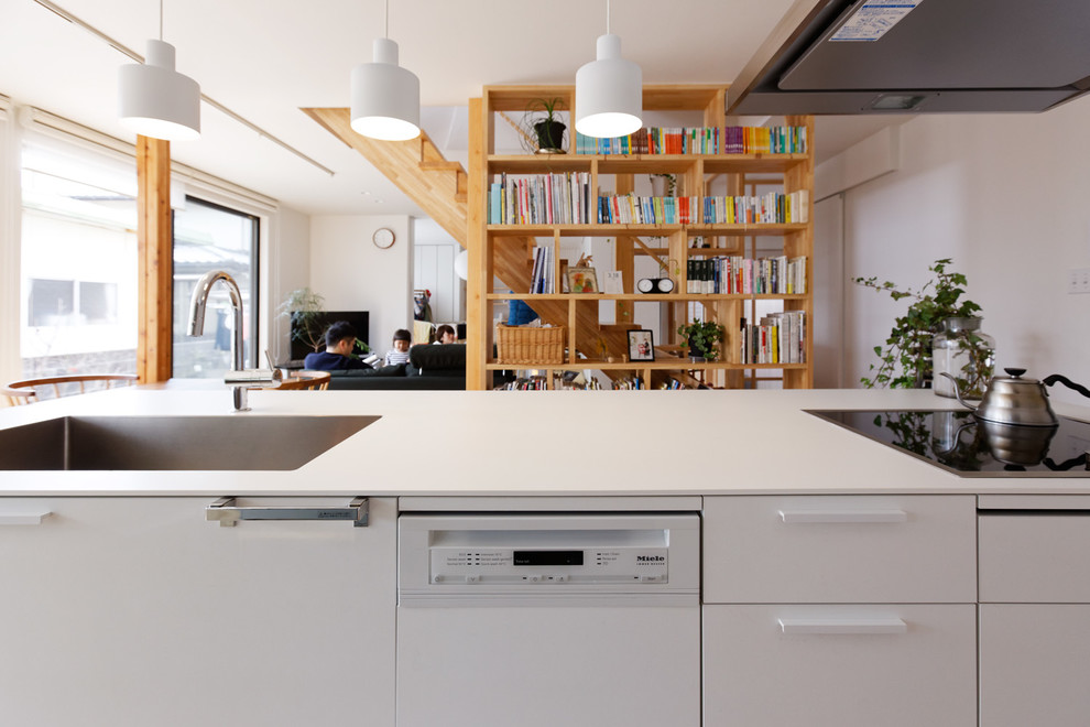 Immagine di una cucina minimalista con lavello sottopiano, ante lisce, ante bianche, paraspruzzi bianco, elettrodomestici in acciaio inossidabile e pavimento marrone