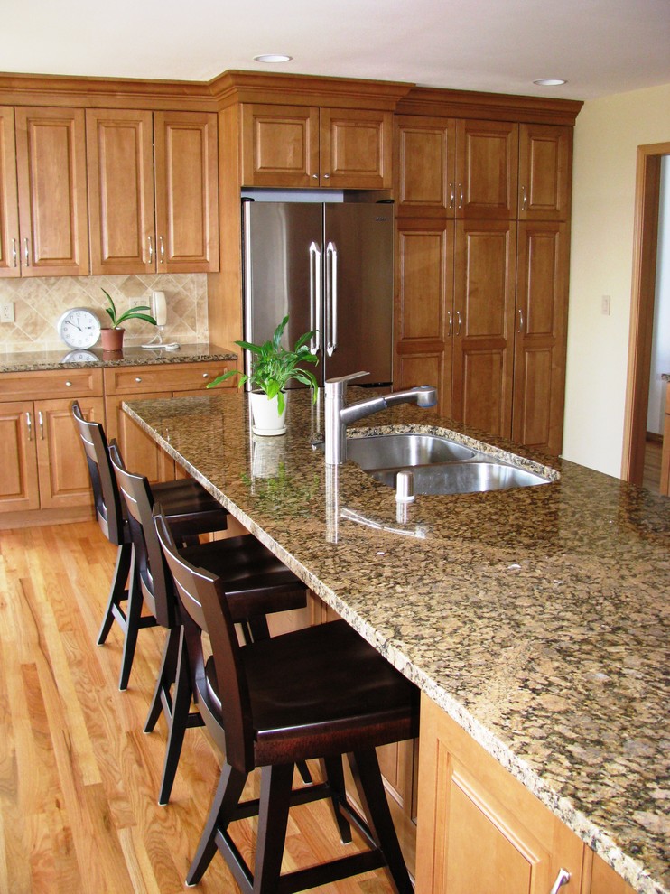 Inspiration for a rustic kitchen remodel in Seattle with an undermount sink, raised-panel cabinets, medium tone wood cabinets, granite countertops, beige backsplash, stone tile backsplash and an island