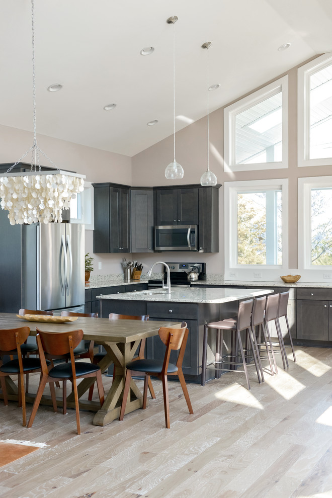 Mid-sized transitional l-shaped light wood floor and brown floor open concept kitchen photo with an undermount sink, shaker cabinets, gray cabinets, granite countertops, stainless steel appliances, an island and gray countertops