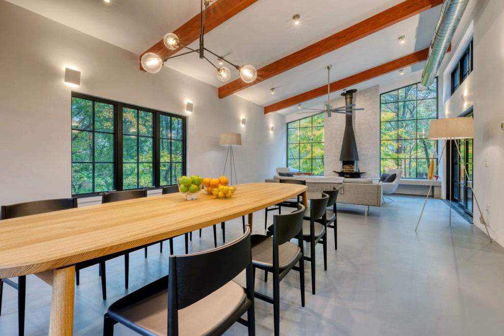 Cette photo montre une grande salle à manger ouverte sur la cuisine moderne avec sol en béton ciré.