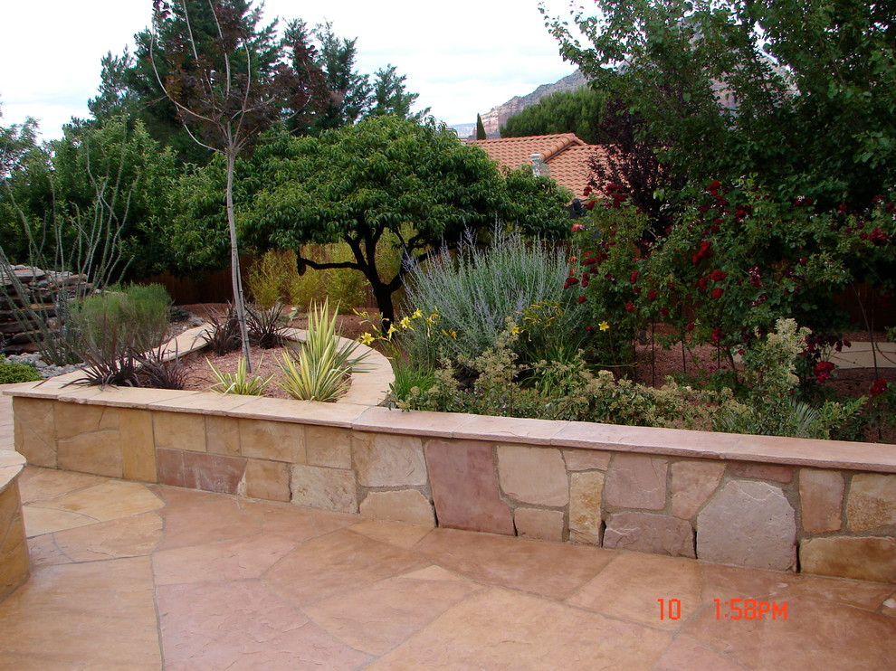 Large backyard patio in Phoenix with a fire feature, natural stone pavers and no cover.