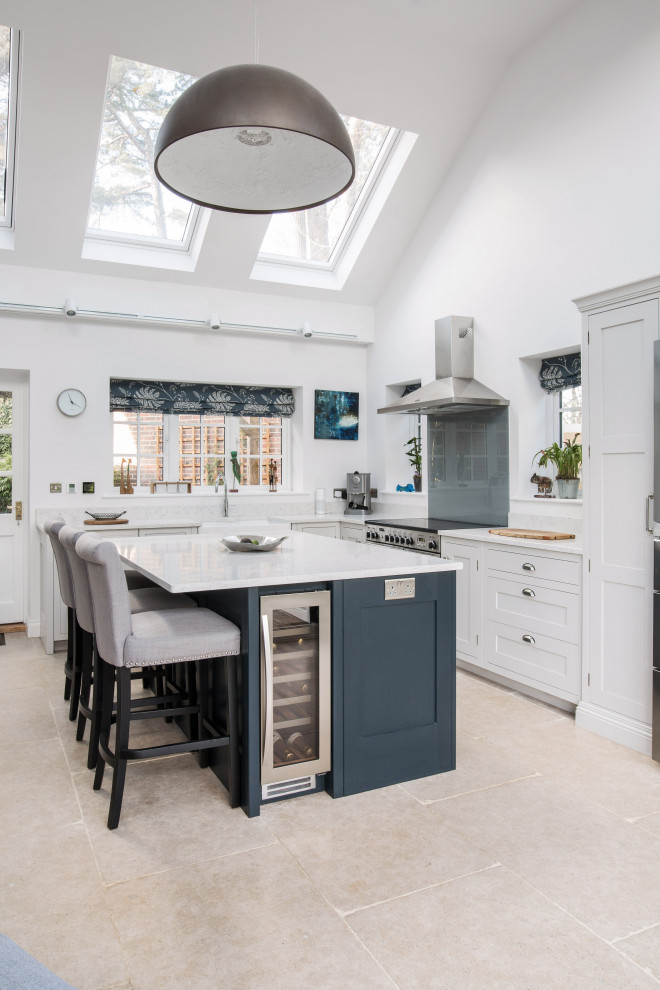 Design ideas for a mid-sized traditional l-shaped separate kitchen in Kent with a farmhouse sink, shaker cabinets, grey cabinets, quartzite benchtops, stainless steel appliances, ceramic floors, with island, beige floor, white benchtop, grey splashback and glass sheet splashback.