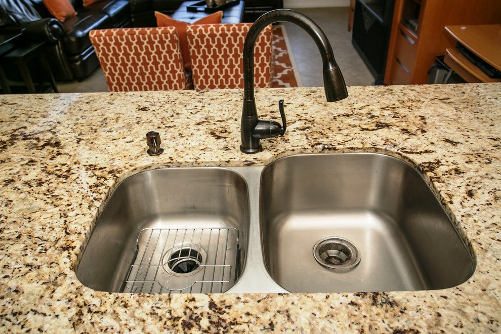 Inspiration for a mid-sized transitional u-shaped porcelain tile eat-in kitchen remodel in Miami with an undermount sink, raised-panel cabinets, brown cabinets, granite countertops, beige backsplash, stone tile backsplash, stainless steel appliances, beige walls and a peninsula