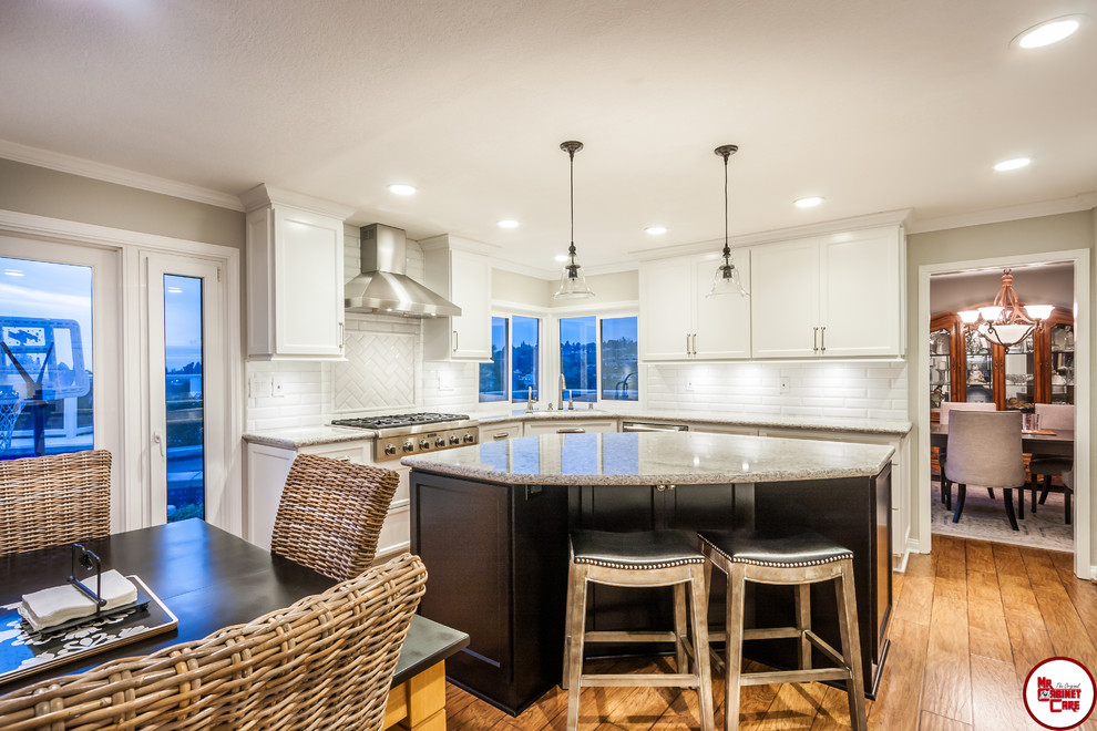 Example of a large transitional l-shaped medium tone wood floor eat-in kitchen design in Orange County with an undermount sink, recessed-panel cabinets, white cabinets, quartz countertops, white backsplash, stainless steel appliances and an island