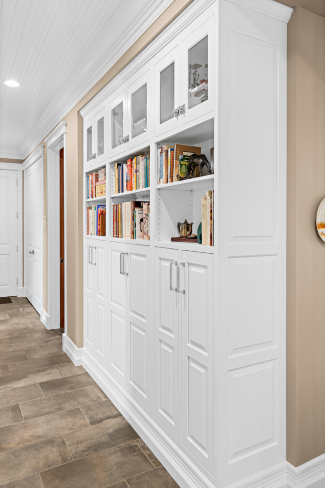 Cette image montre un couloir design de taille moyenne avec un mur blanc, un sol en carrelage de porcelaine, un sol marron et un plafond en lambris de bois.
