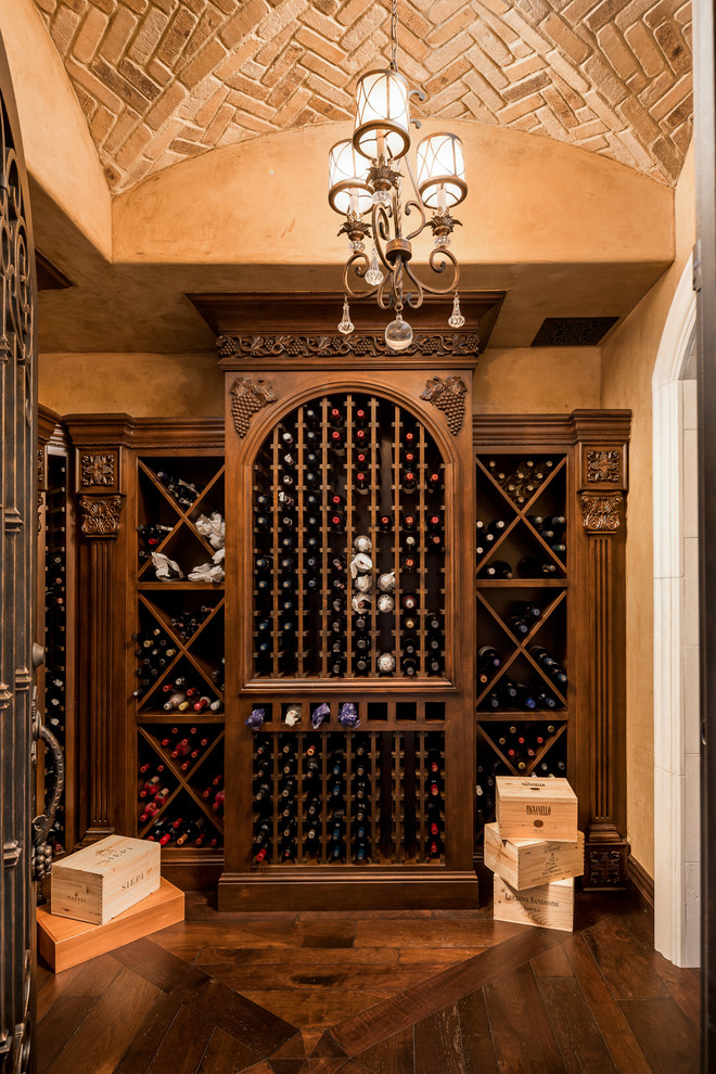 Photo of an expansive mediterranean wine cellar in Austin with dark hardwood floors, storage racks and brown floor.