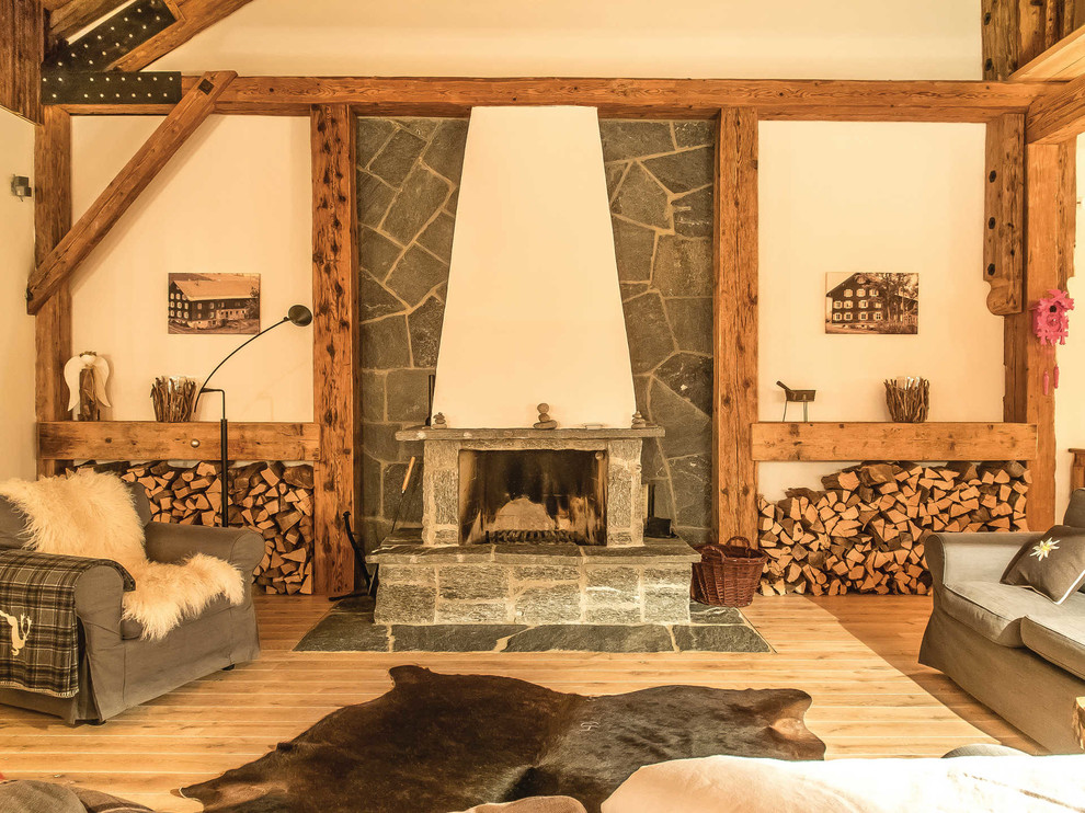 Inspiration for a mid-sized country enclosed family room in Munich with beige walls, light hardwood floors, a wood stove, a stone fireplace surround, no tv and brown floor.