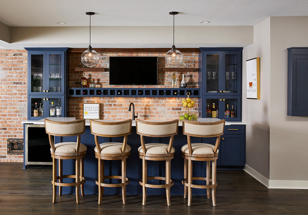 This is an example of a mid-sized transitional galley wet bar in Minneapolis with an undermount sink, blue cabinets, quartzite benchtops, brick splashback, vinyl floors, brown floor, white benchtop, glass-front cabinets and orange splashback.