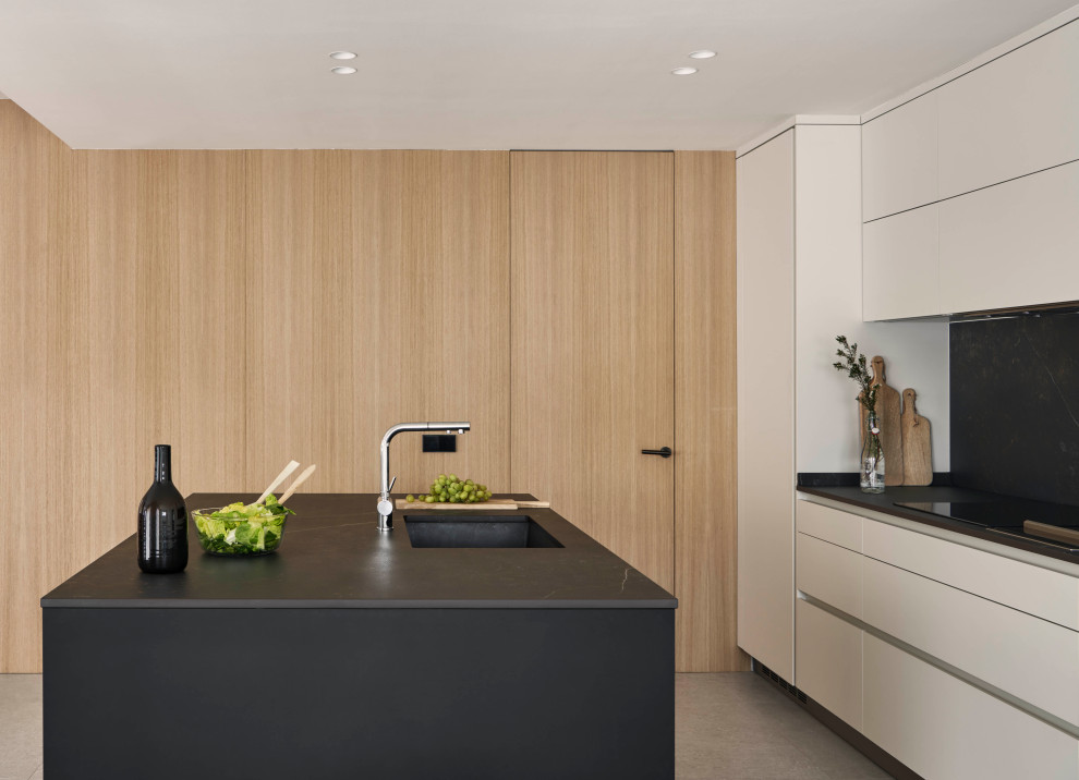 Cette photo montre une grande cuisine grise et noire moderne avec un placard avec porte à panneau encastré, des portes de placard blanches, sol en béton ciré, îlot et un sol gris.