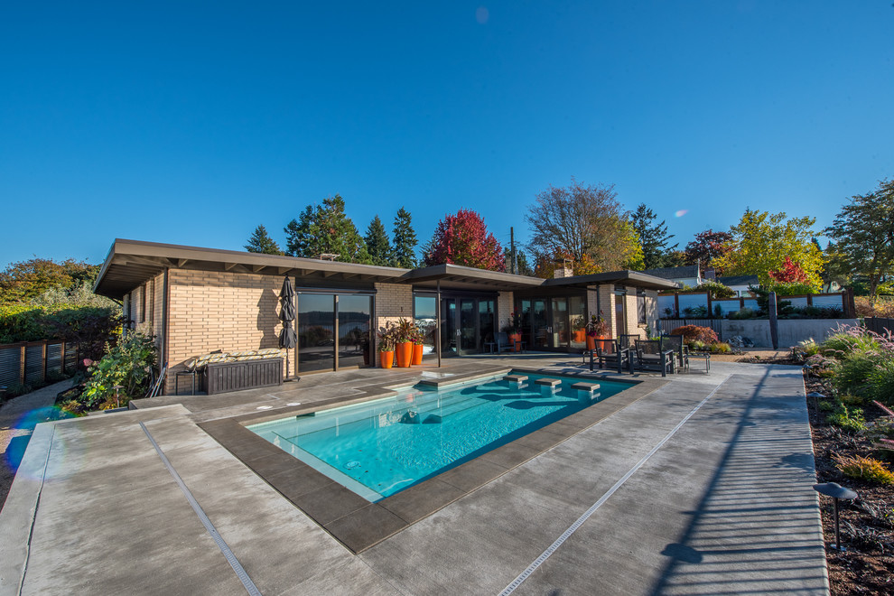 Inspiration for a mid-sized contemporary backyard rectangular pool in Seattle with concrete slab.
