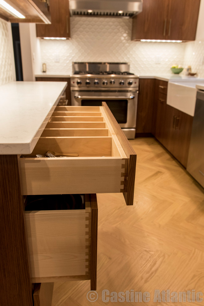 This is an example of a mid-sized modern l-shaped separate kitchen in New York with a farmhouse sink, medium wood cabinets, quartzite benchtops, white splashback, stainless steel appliances, light hardwood floors, yellow floor and ceramic splashback.
