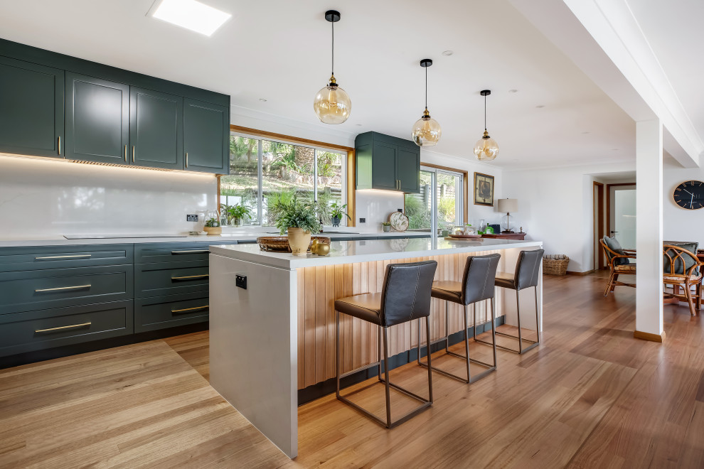 Large transitional l-shaped medium tone wood floor and multicolored floor eat-in kitchen photo in Sydney with a drop-in sink, shaker cabinets, green cabinets, quartz countertops, white backsplash, quartz backsplash, black appliances, an island and white countertops