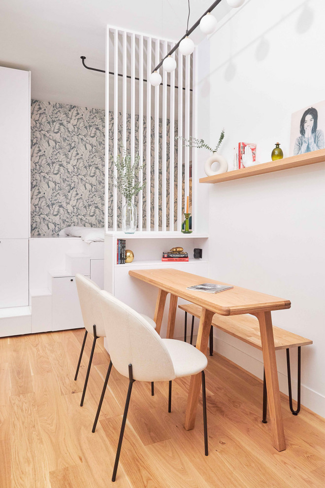На фото: маленькая гостиная-столовая в стиле модернизм с белыми стенами, светлым паркетным полом и обоями на стенах для на участке и в саду
