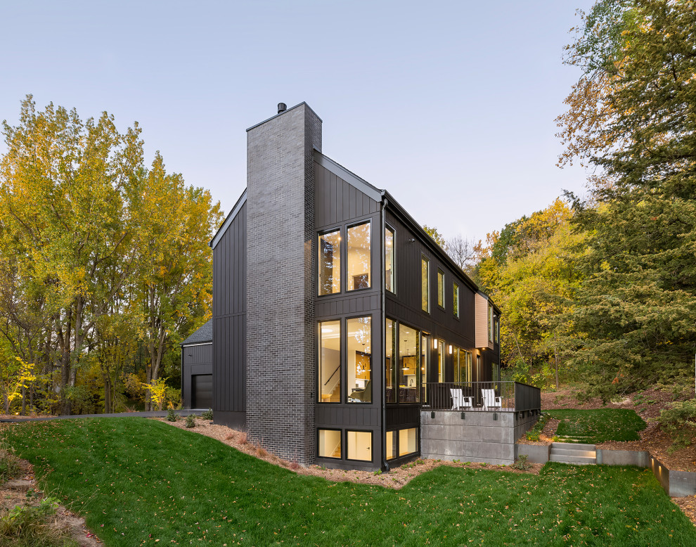 Großes, Zweistöckiges Nordisches Haus mit schwarzer Fassadenfarbe, Satteldach, Schindeldach, schwarzem Dach und Wandpaneelen in Minneapolis