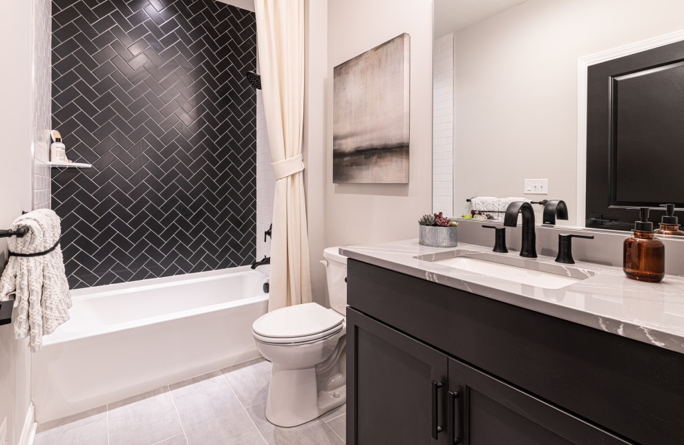 This is an example of a transitional 3/4 bathroom in Wilmington with shaker cabinets, black cabinets, an alcove tub, a shower/bathtub combo, a two-piece toilet, black tile, white walls, an undermount sink, grey floor, a shower curtain and grey benchtops.