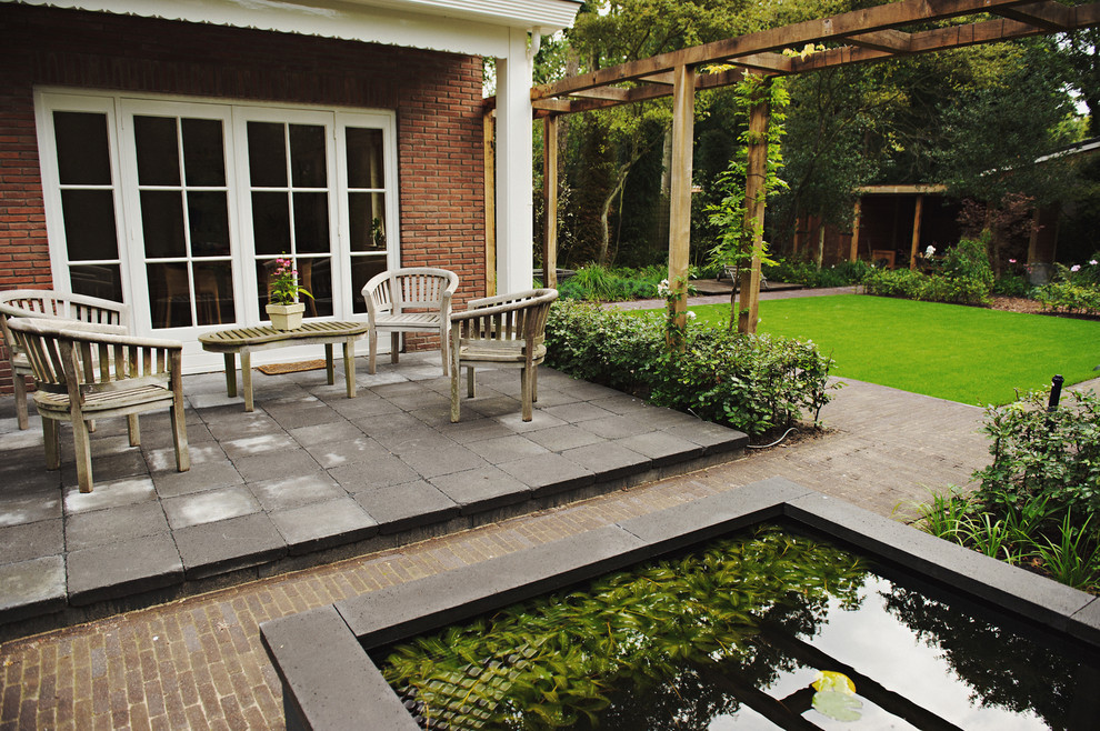 Photo of a traditional garden in Amsterdam with brick pavers and a water feature.