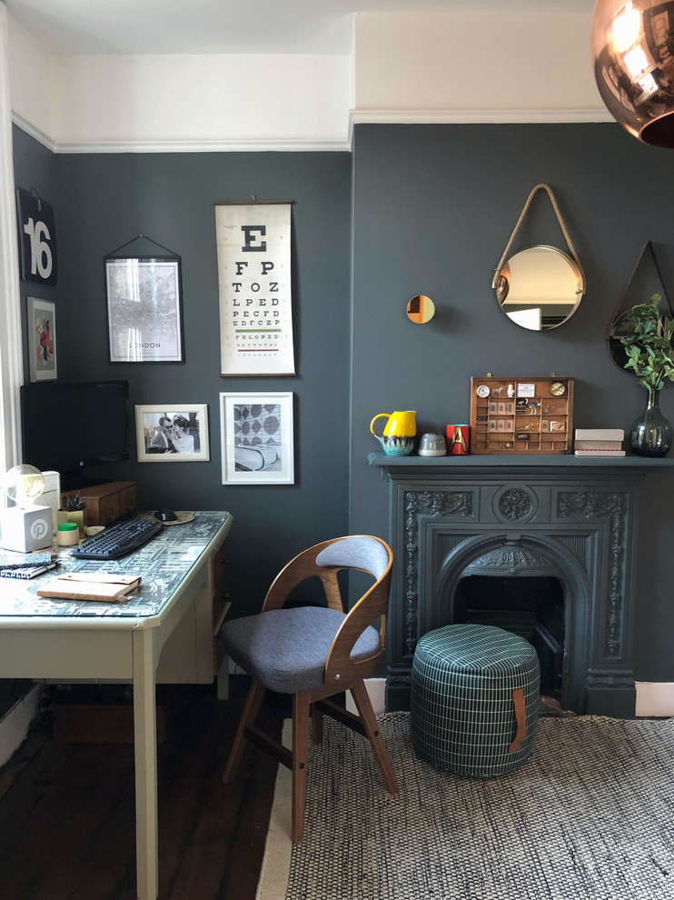 Photo of a mid-sized transitional study room in London with grey walls, dark hardwood floors, a standard fireplace, a metal fireplace surround, a freestanding desk and brown floor.