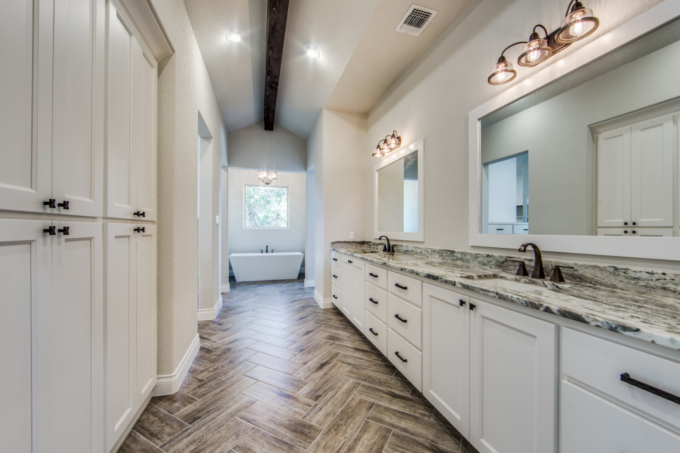 Large country master bathroom in Austin with porcelain floors, recessed-panel cabinets, white cabinets, a freestanding tub, an open shower, a two-piece toilet, brown tile, porcelain tile, grey walls, an undermount sink, granite benchtops, brown floor, an open shower and multi-coloured benchtops.